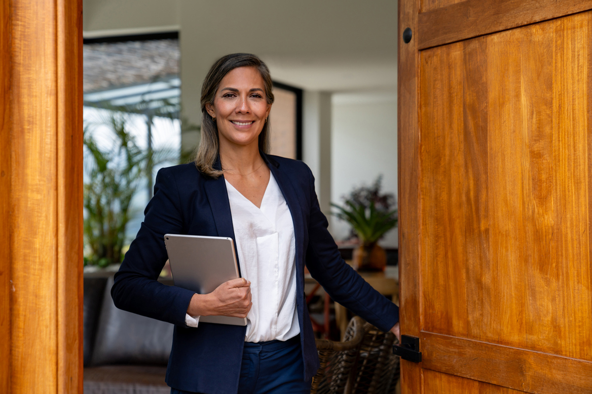 Real estate agent holding open a door