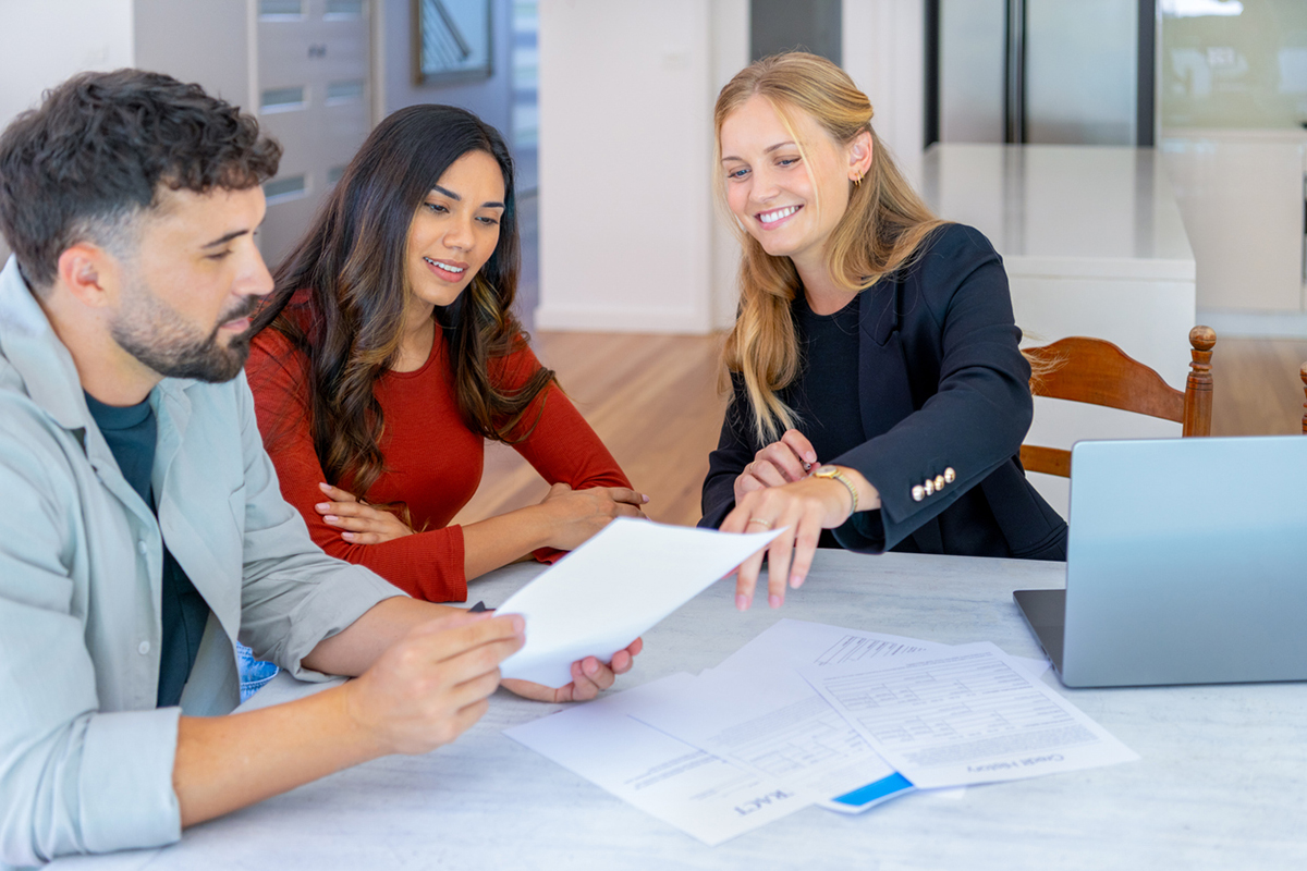 Two homebuyers looking over paperwork with a real estate agent