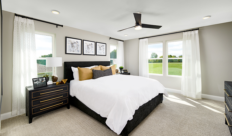 Spacious Moonstone plan primary suite with ample windows and a ceiling fan