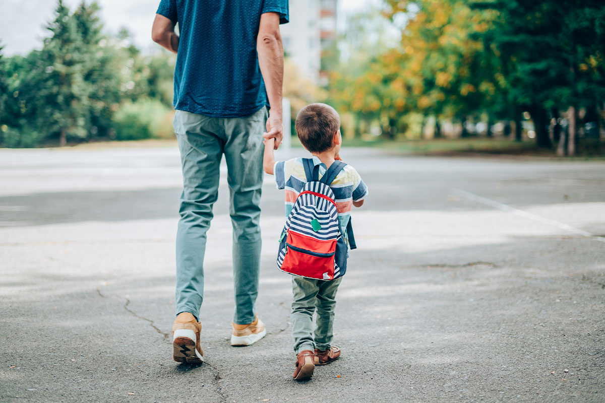 Dad walking young son with a backpack to school