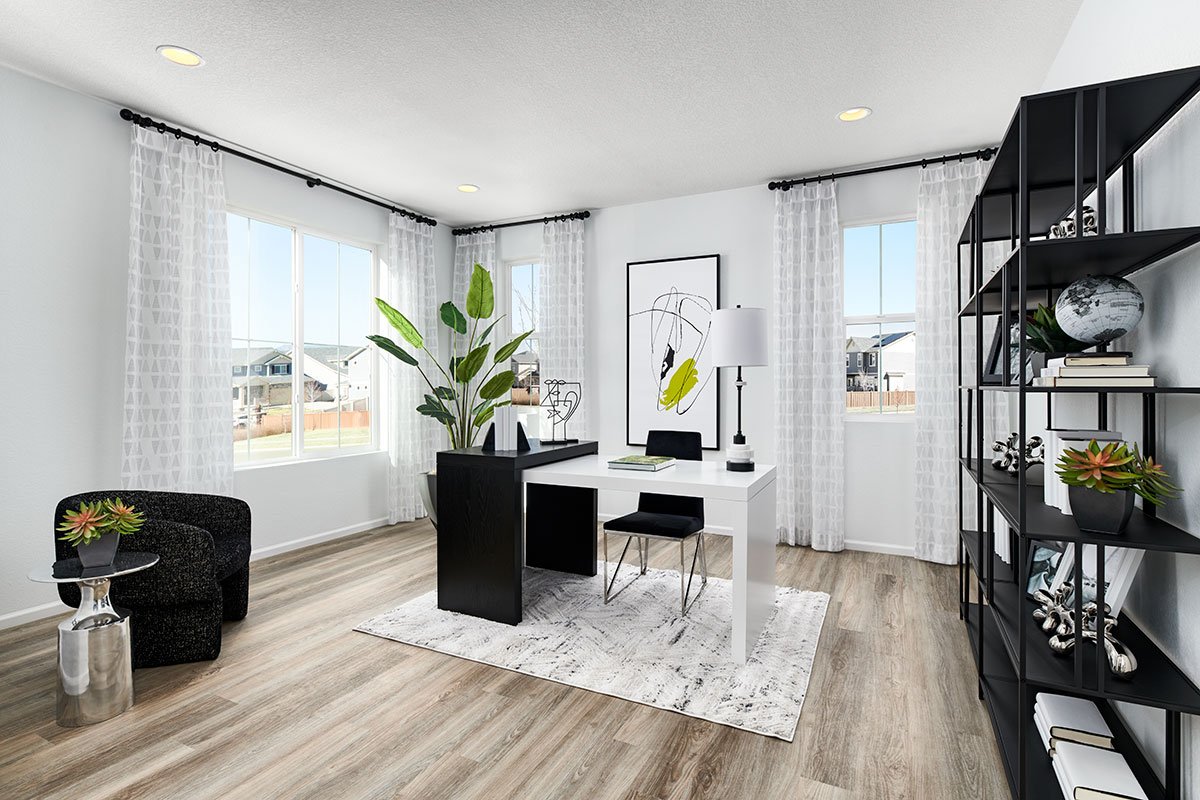 Clean home office with a desk, shelves, sitting area and windows. 