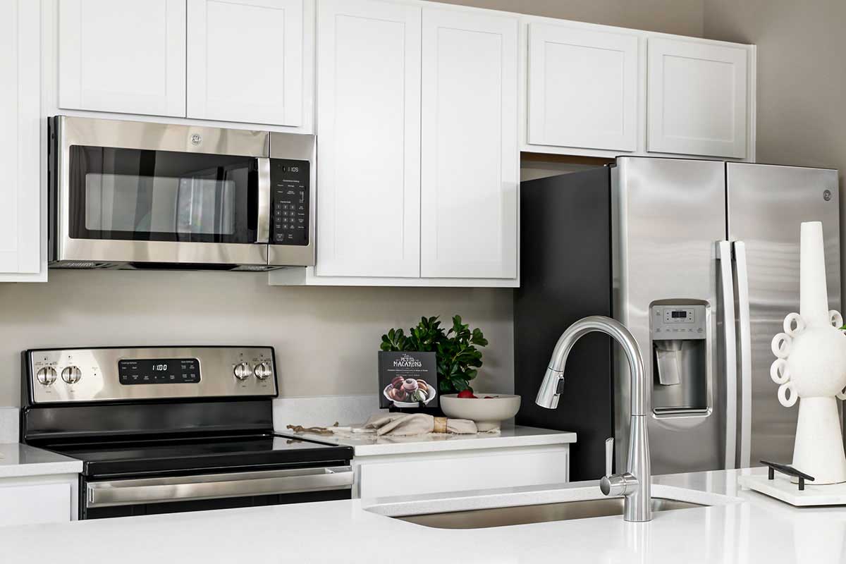 Tidy kitchen with white counter tops and stainless steel appliances