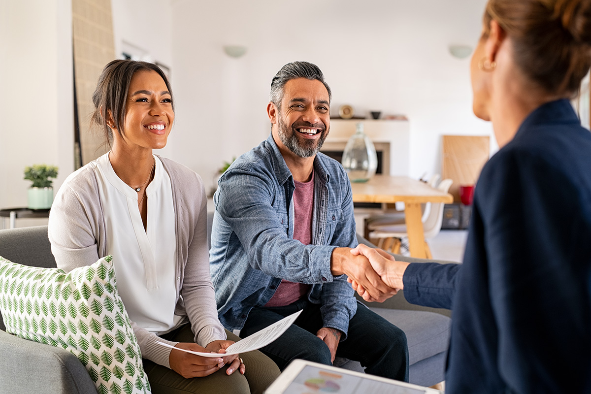 Two happy homebuyers shaking hands with a sales associate