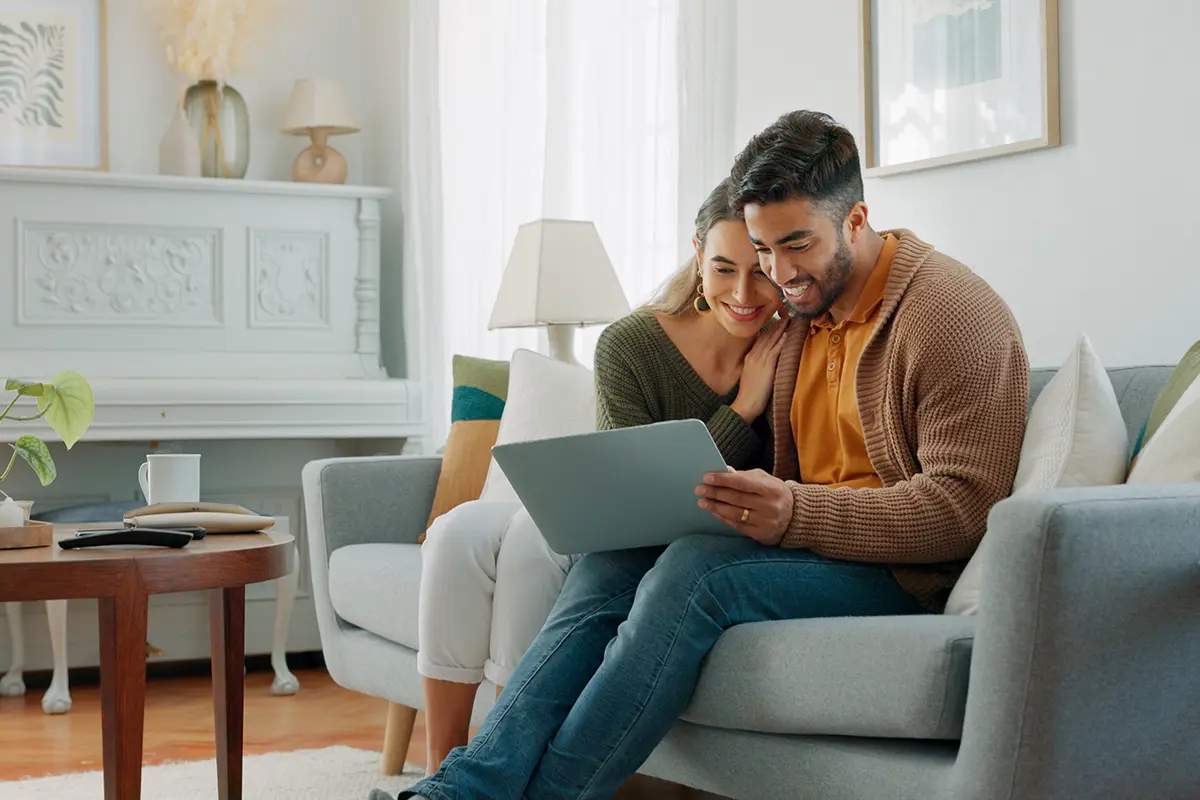 Couple on couch researching mortage rates on the computer