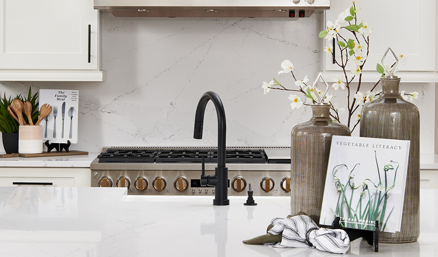 Image of curated kitchen with black faucet, white cabinets and countertops and stainless steel appliance