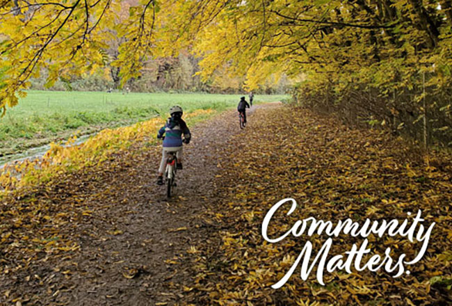 Kids biking on a path with in the fall with leaves on the ground