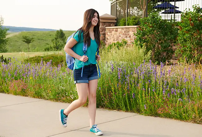 Teenage girl walking on the sidewalk with a backpack