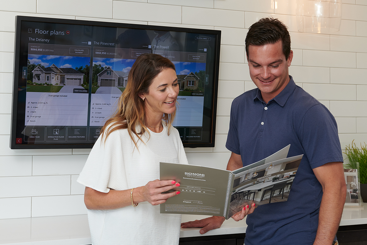 Woman holding brochure for her and man standing next to her to review