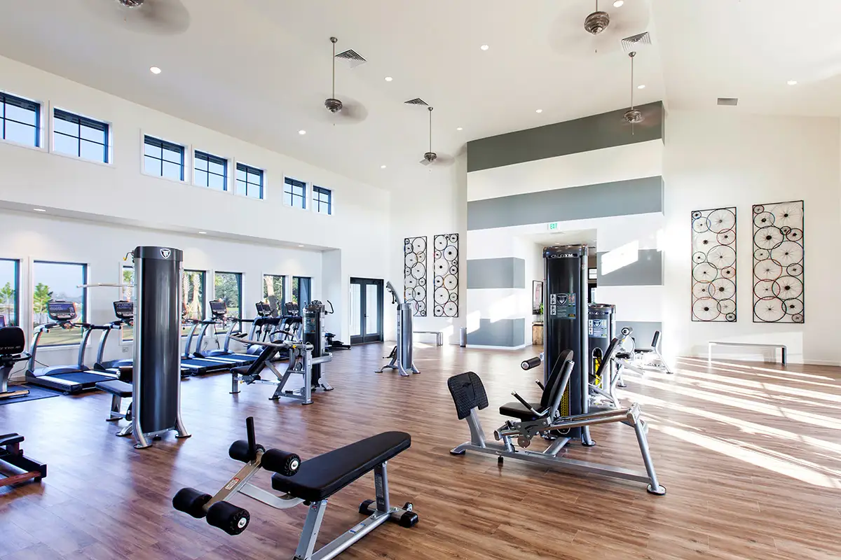 Community gym with tall ceilings, wood floors, and several machines