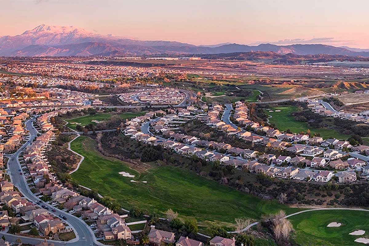 Aerial view of a community with a golf course and mountains in the background